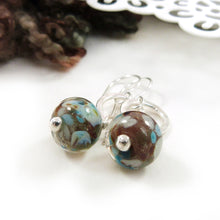 Pair of earrings with brown and blue beads on a white surface
