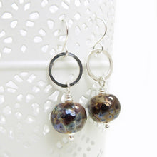 Pair of earrings with round brown beads and silver loops on a white background
