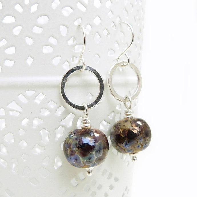 Pair of earrings with round brown beads and silver loops on a white background