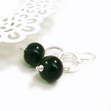 Green beaded earrings with silver hooks on a white background