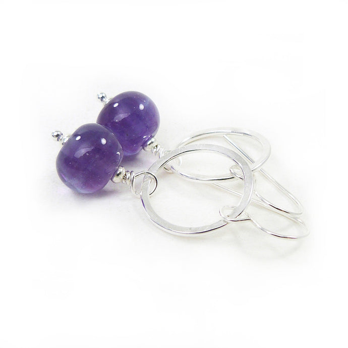 Silver hoop earrings with purple beads on a white background