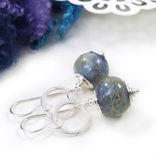 Pair of silver earrings with blue glass beads on a white background