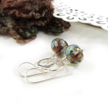 Pair of earrings with brown and blue beads on a white surface