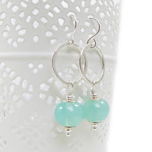 Silver earrings with green beads on a white background