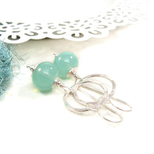 Silver earrings with green beads on a white background