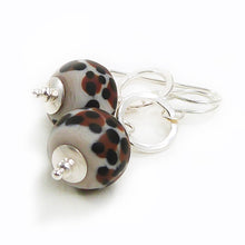 Pair of earrings with leopard print beads and silver hooks on a white background