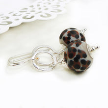 Pair of earrings with leopard print beads and silver hooks on a white background