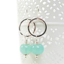 Silver earrings with green beads on a white background