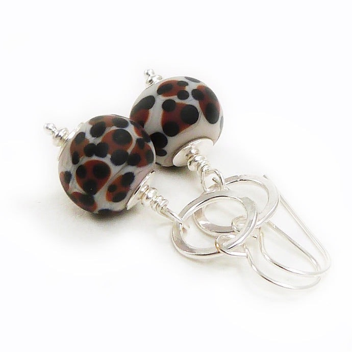 Pair of earrings with leopard print beads and silver hooks on a white background
