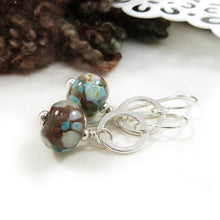 Pair of earrings with brown and blue beads on a white surface