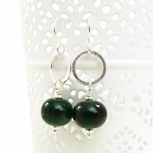 Green beaded earrings with silver hooks on a white background