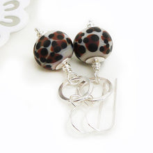 Pair of earrings with leopard print beads and silver hooks on a white background