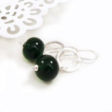 Green beaded earrings with silver hooks on a white background