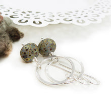 Silver Circle and speckled glass bead drop earrings on a white background