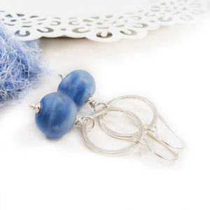 Blue beaded earrings with silver loops on a white background