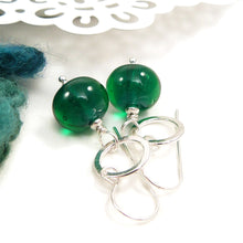 Green bead earrings with silver hooks on a white background