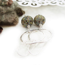 Silver Circle and speckled glass bead drop earrings on a white background