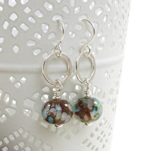 Pair of earrings with brown and blue beads on a white surface