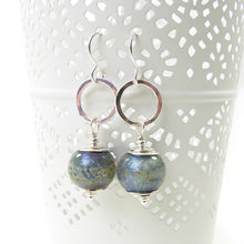 Pair of silver earrings with blue glass beads on a white background