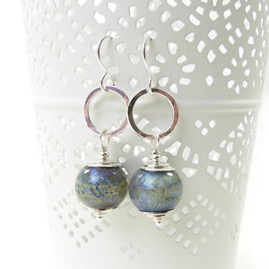 Pair of silver earrings with blue glass beads on a white background