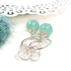 Silver earrings with green beads on a white background