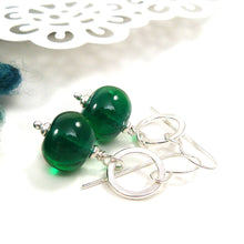 Green bead earrings with silver hooks on a white background
