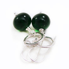 Green beaded earrings with silver hooks on a white background