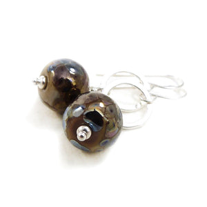 Pair of earrings with round brown beads and silver loops on a white background