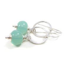 Silver earrings with green beads on a white background