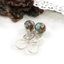 Pair of earrings with brown and blue beads on a white surface