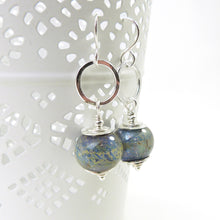 Pair of silver earrings with blue glass beads on a white background