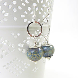 Pair of silver earrings with blue glass beads on a white background