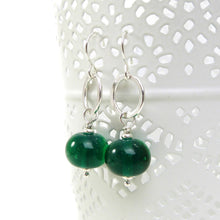 Green bead earrings with silver hooks on a white background