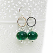 Pair of earrings with green beads and silver rings on a white background