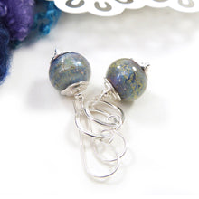 Pair of silver earrings with blue glass beads on a white background