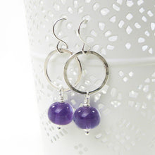 Silver hoop earrings with purple beads on a white background