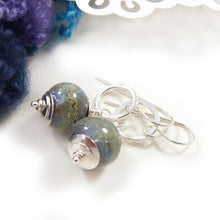 Pair of silver earrings with blue glass beads on a white background