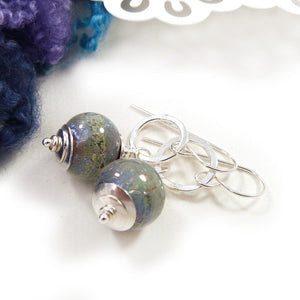 Pair of silver earrings with blue glass beads on a white background