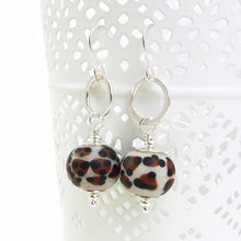 Pair of earrings with leopard print beads and silver hooks on a white background