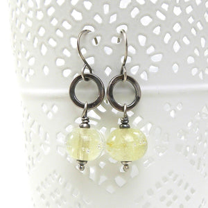 Silver earrings with translucent pale Yellow beads on a white background