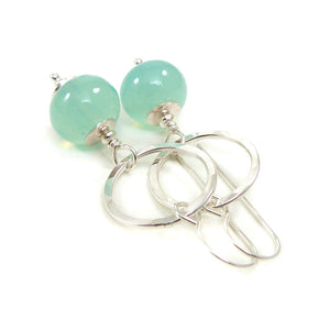 Silver earrings with green beads on a white background