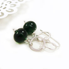 Green beaded earrings with silver hooks on a white background