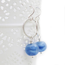 Silver earrings with blue beads on a white background