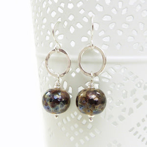 Pair of earrings with round brown beads and silver loops on a white background