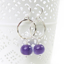 Silver hoop earrings with purple beads on a white background