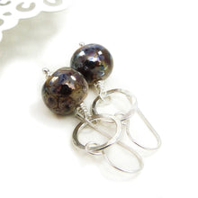 Pair of earrings with round brown beads and silver loops on a white background