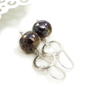 Pair of earrings with round brown beads and silver loops on a white background
