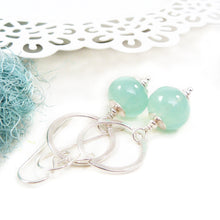 Silver earrings with green beads on a white background