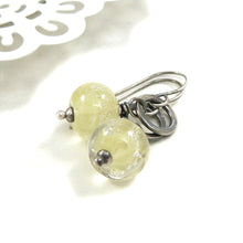 Silver earrings with translucent pale Yellow beads on a white background