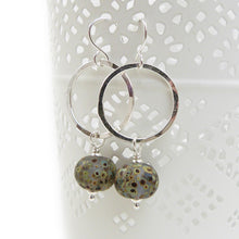 Silver Circle and speckled glass bead drop earrings on a white background